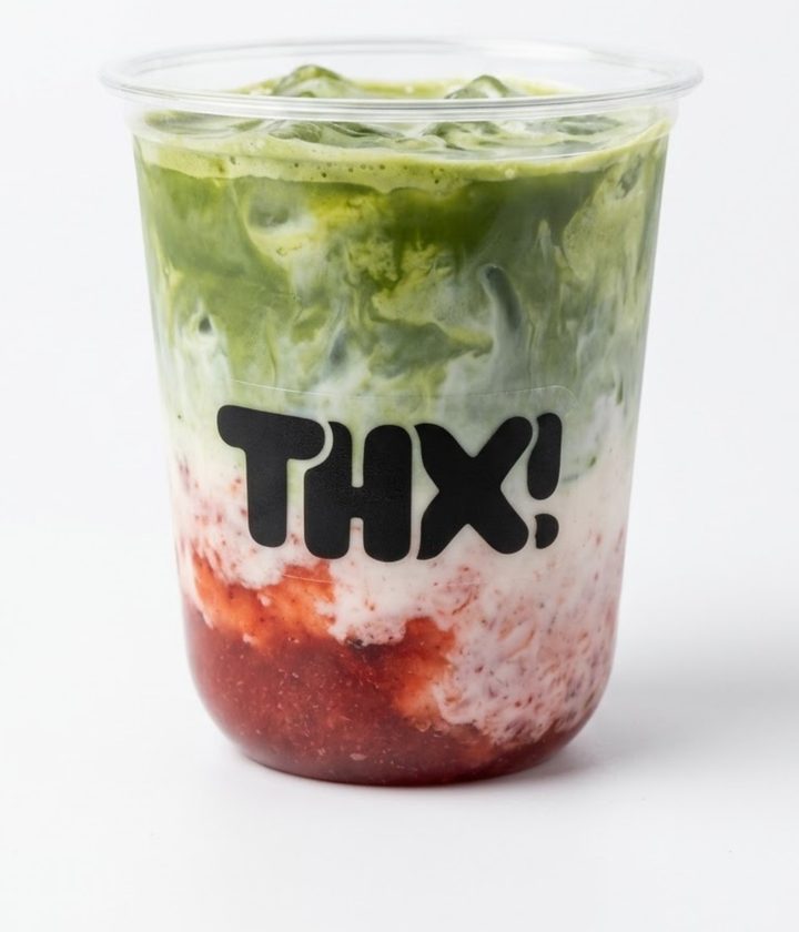 Iced strawberry matcha with layers of strawberry, milk, and green matcha in a clear thx! cup